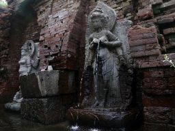 Patung yang menempel pada dinding candi yang tersusun dari bata merah ni memancarkan sumber air.