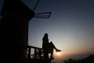 Seorang wisatawan melihat indahnya matahari terbit atau sunrise dari Bukit Kuneer, salah satu spot wisata yang ada di Agrowisata Wonosari Kebun Teh Wonosari, Kabupaten Malang, Jawa Timur, Rabu (25/9/2024).