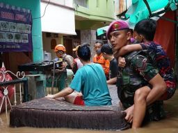 Prajurit Korps Marinir TNI AL menggendong anak yang terjebak banjir dan mengevakuasi warga dengan perahu karet