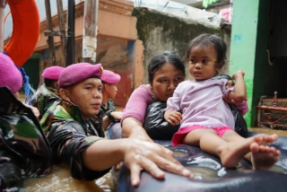 Prajurit Korps Marinir TNI AL membantu warga yang terjebak banjir.