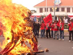 Massa aksi membakar replika patung babi berdasi ketika menggelar aksi peringatan Hari Buruh atau May Day 2025 di depan Gedung Negara Grahadi