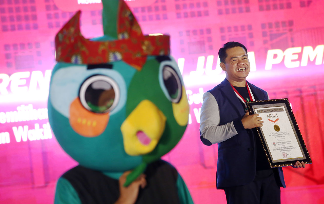 Ketua KPU Jatim Aang Kunaifi membawa Piagam Penghargaan Rekor MURI saat Gebyar Coklit Serentak Satu Juta Pemilih Pilkada Jatim 2024 di Surabaya, Senin (24/6/2024) malam. Foto/Alim Perdana