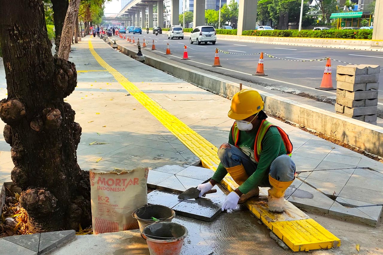 Proses pemasangan batu andesit untuk pekerjaan konstruksi revitalisasi trotoar di kawasan Jalan HR Rasuna Said, Kuningan, Jakarta.Foto/SIG