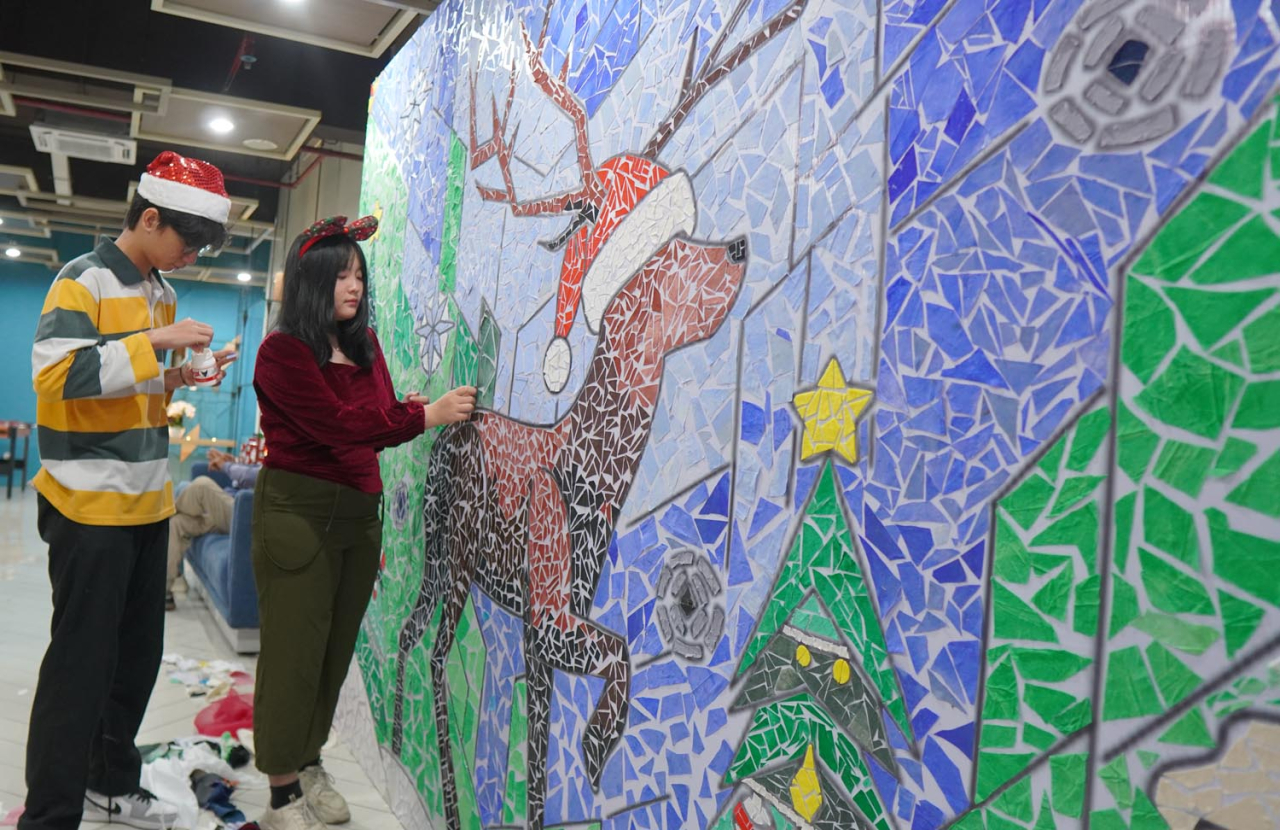 Louis Michael Tjoeng (kiri) dan Felicia Oentoro (kanan) menempel potongan kain membentuk mozaik Natal. Foto/Humas Ubaya
