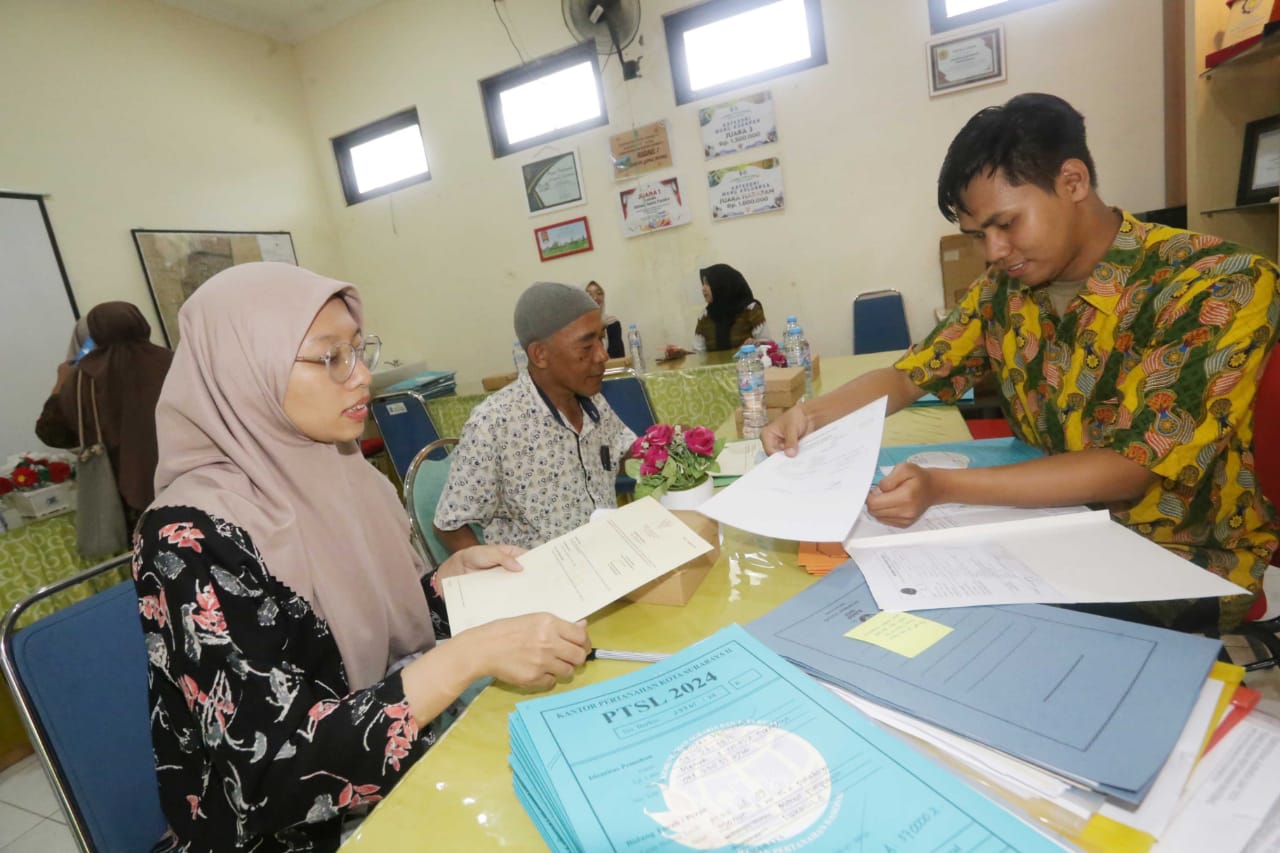 Salah seorang warga menerima sertifikat melalui program PTSL di kelurahan menur pumpungan Surabaya, kamis (5/12/2024). Foto/Ayojatim