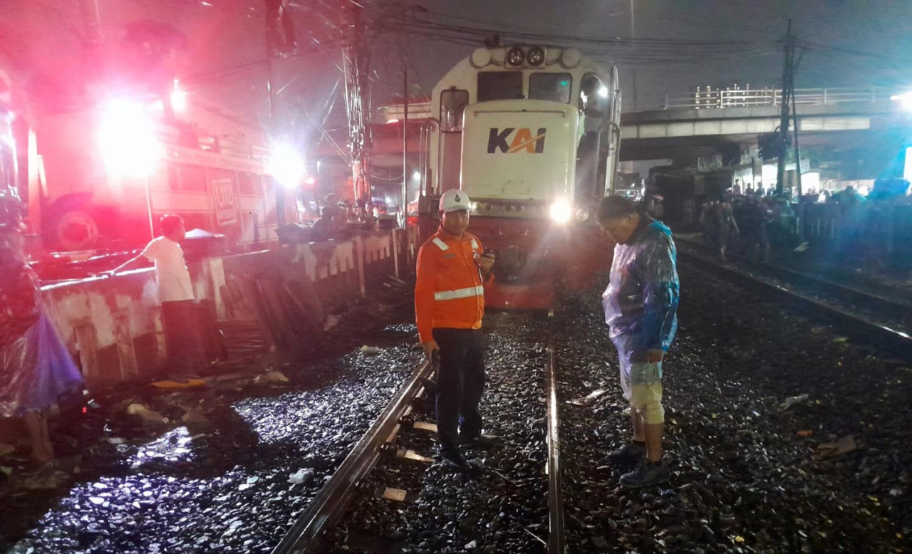 Petugas KAI bergerak cepat untuk mengevakuasi mobil yang menghalangi jalur kereta api. Foto/Humas KAI