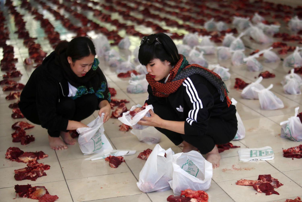 Mahasiswi Satsunan University Osaka Jepang program Student Exchange, membantu membungkus daging kurban yang akan dibagikan pada masyarakat, di Unitomo Surabaya. Foto/Ali Masduki