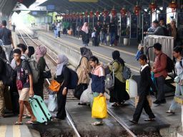 Calon penumpang kereta api menyeberang rel di Stasiun Surabaya Gubeng, Selasa (28/1/2025).